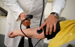 Ein Hausarzt misst den Blutdruck bei einem Patienten.