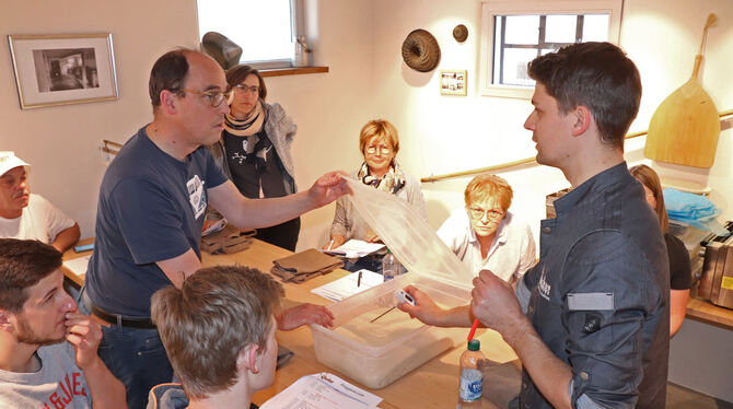 Simon Glocker (rechts) erklärt den Teilnehmern seiner Backkurse in der alten Mühlenscheune in Gomadingen, wie die Beschaffenheit