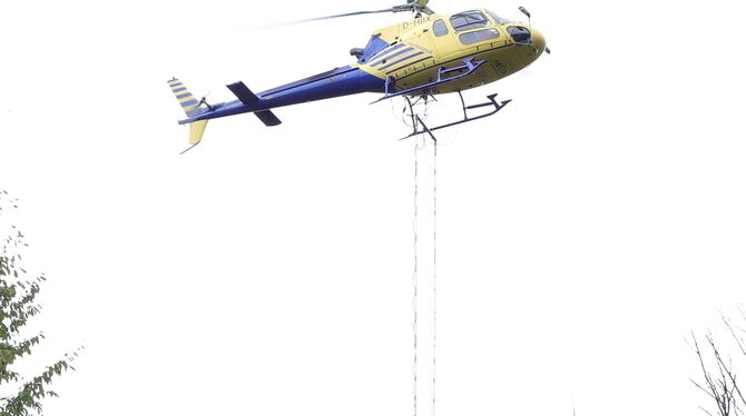Kurz steht der Hubschrauber zum Nachfüllen über dem Radlader, dann wird der Kalk wieder über den Wipfeln verteilt. Der Heli schl