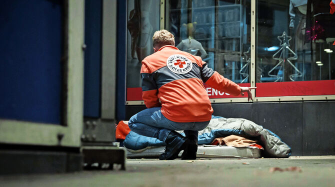 Ein Helfer kümmert sich um einen auf der Straße schlafenden Obdachlosen.  FOTO: RETTIG/LICHTGUT