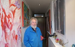 Der Kunstmaler Gernot Dilger steht in seinem Flur zwischen seinen Werken.  FOTO: KLEIN