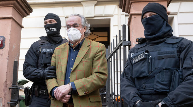 Polizisten führen Heinrich XIII. Prinz Reuß in Handschellen ab.  FOTO: ROESSLER/DPA