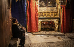 Eine Frau sitzt in der Geburtsgrotte der Geburtskirche von Bethlehem.