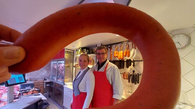 Wilfried und Anette Schneider – hier durch einen Ring Fleischwurst gesehen – schaffen gern, ihr Laden läuft. Trotzdem schließen