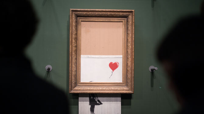 Besucher stehen vor dem Banksy-Bild »Love is in the Bin«. Das Bild zerstörte sich nach einer Auktion selbst.  FOTO: GOLLNOW/DPA