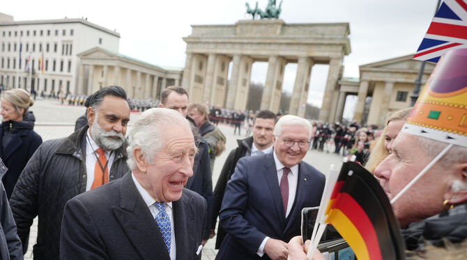 König Charles III. amüsiert sich königlich über einen Mann mit Papp-Krone, Bundespräsident Steinmeier schaut zu.  FOTO: NIETFEL