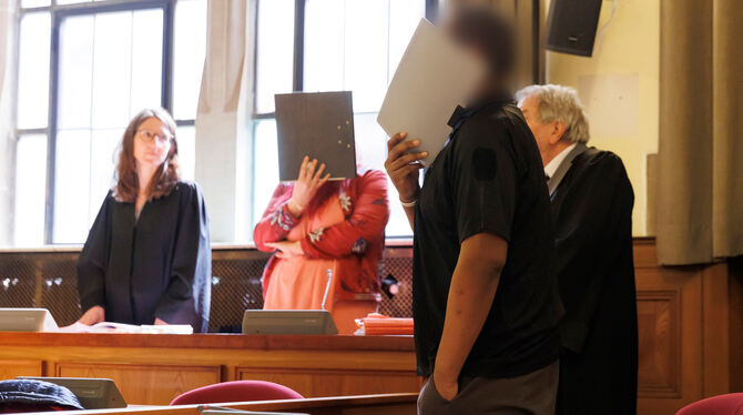 Die beiden Angeklagten verdecken im Gerichtssaal vor Sitzungsbeginn ihre Gesichter. Auftakt der Verhandlung vor dem Landgericht