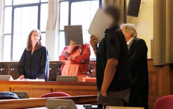 Die beiden Angeklagten verdecken im Gerichtssaal vor Sitzungsbeginn ihre Gesichter. Auftakt der Verhandlung vor dem Landgericht 