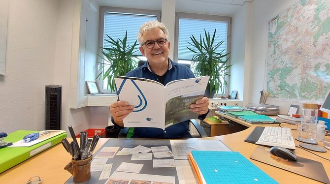 Arno Valin am Schreibtisch mit seinem mutmaßlich schönsten Abschiedsgeschenk: Der »Leitfaden Regenwasser Reutlingen« findet  lan