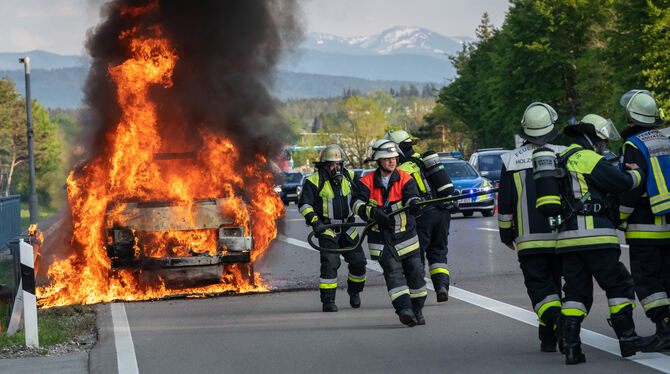 Nur mit viel Wasser und viel Zeit löschbar: Ein brennendes E-Auto auf einer Straße.