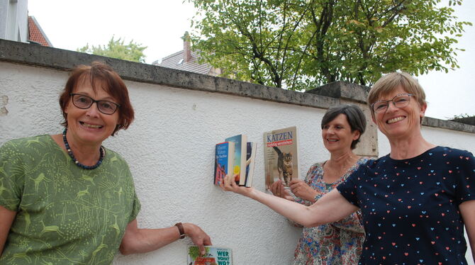 Drei Initiatorinnen des Metzinger Bücherschranks an der Wand zwischen Rathaus und Spielplatz, an der der Schrank mal stehen könn