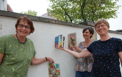 Drei Initiatorinnen des Metzinger Bücherschranks an der Wand zwischen Rathaus und Spielplatz, an der der Schrank mal stehen könn