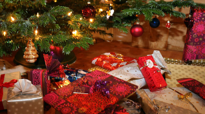 Verpackte Weihnachtsgeschenke liegen unter einem Christbaum.  FOTO: HILDENBRAND/DPA