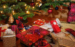 Verpackte Weihnachtsgeschenke liegen unter einem Christbaum.  FOTO: HILDENBRAND/DPA