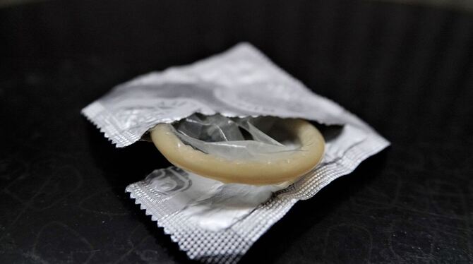 Eine geöffnete Kondompackung liegt auf einem Nachttisch