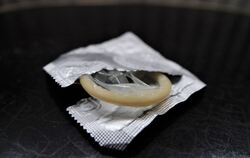 Eine geöffnete Kondompackung liegt auf einem Nachttisch