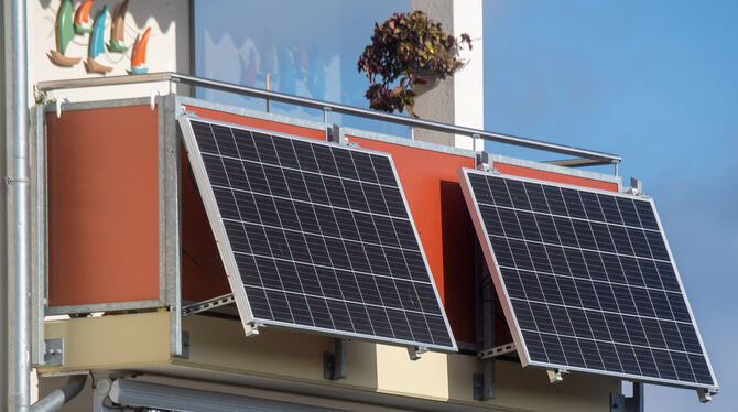 Solarmodule für ein  Balkonkraftwerk hängen an einem Balkon. So kann jeder Stromproduzent werden.
