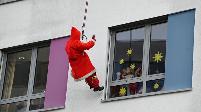 Verkleidet als Weihnachtsmann seilt sich ein Höhenretter winkend am Klinikum am Steinenberg ab.