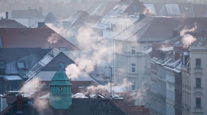Rauch strömt aus den Kaminen auf den Dächern der Mehrfamilienhäuser im Leipziger Süden an einem kalten Wintermorgen. Unterhändl