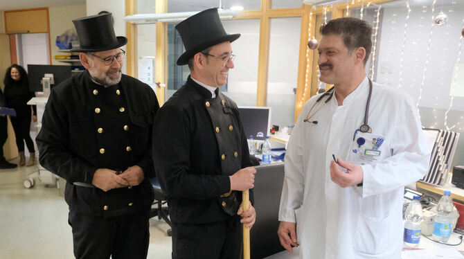 Schornsteinfeger Joachim Gräther und Jörg Zimmer überreichen einem ärztlichen Mitarbeiter der Klinik einen Glücksbringer.  FOTO: