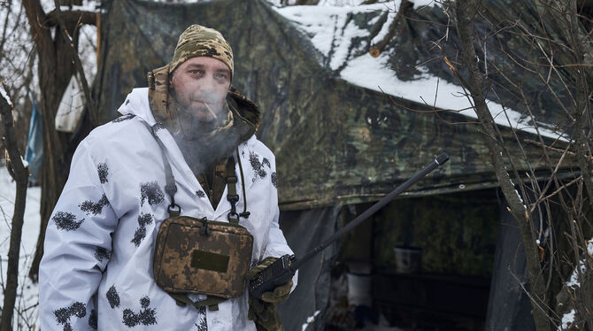 Ein ukrainischer Soldat steht in der Kälte bei Eis und Schnee vor einem Zelt vor einem Zelt an der Front im Gebiet Donezk.