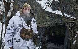 Ein ukrainischer Soldat steht in der Kälte bei Eis und Schnee vor einem Zelt vor einem Zelt an der Front im Gebiet Donezk. 