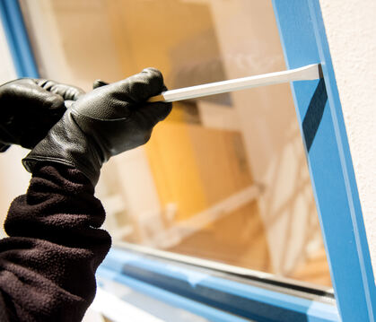 Ein Einbrecher auf Beutezug versucht mit einem Schraubenzieher ein Fenster aufzuhebeln.