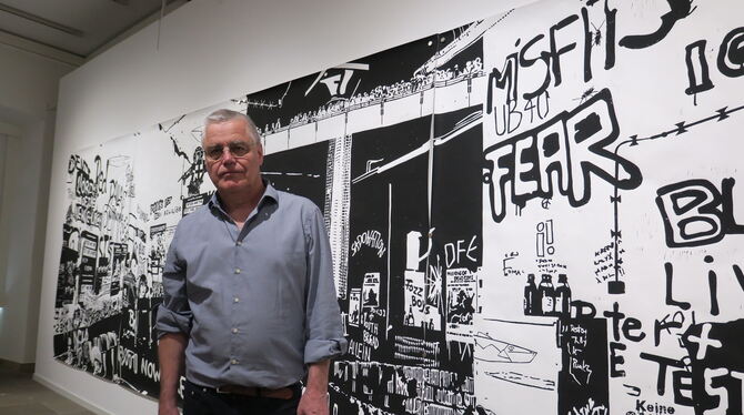 Florian Haas vor einem wandfüllenden Linoldruck, auf dem er in die Hausbesetzerszene der 1980er in Freiburg abtaucht.