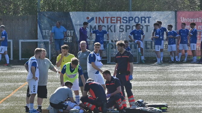 Sanitäter und Notarzt auf dem Spielfeld versorgen den am Ellbogen verletzten Pfullinger Verteidiger Sven Packert.