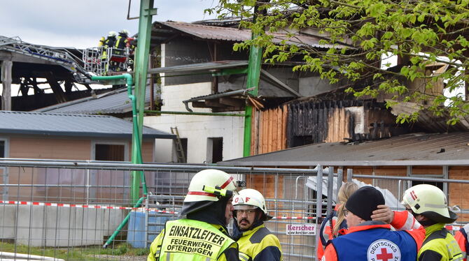 Einsatzkräfte am Samstag vor der Brandruine, wo die Drehleiterbesatzung ein aufgelodertes Feuer bekämpft.
