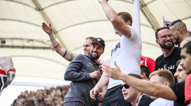 Stuttgarts Trainer Sebastian Hoeneß (grauer Anzug)  jubelt nach dem Spiel auf dem Zaun mit den VfB-Fans.