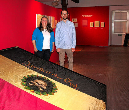 Eva Bissinger und Sven-Jan Reinacher kuratieren die Ausstellung und stehen hinter der Revolutionsfahne „Freiheit oder Tod“.