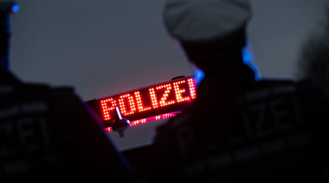 Zwei Polizisten stehen vor einem Polizeifahrzeug (Symbolbild).