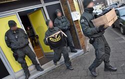 Polizisten tragen in Duisburg bei einer Durchsuchung des Vereinsheims des Rockerclubs "Satudarah Maluku MC" Beweismaterial aus d