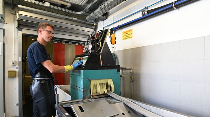 Feuerwehr-Azubi Alex Weiß an der Schlauchwaschanlage. Im grünen Kasten stecken Bürsten, die den Dreck am Gewebe entfernen.