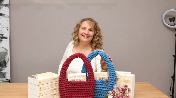 Maria Nikolai Besteller-Autorin Maria Nikolai zwischen Band 1 und 2 der Little-Germany-Dilogie und zwei gehäkelten Taschen, in die die Bücher