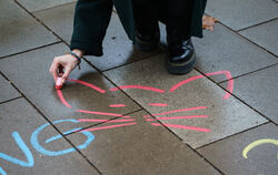 Eine Aktivistin malt mit Kreide ein Katzensymbol neben einen anzüglichen Kommentar aufs Straßenpflaster. Mit diesen Aktionen mac