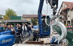 Markus Steinhart zeigte den Gemeinderäten mit seinem Bagger, wie sich die vorbereiteten Steine auf die Straße setzen lassen.