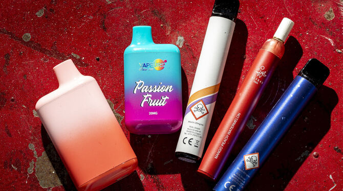 Mehrere Einweg-E-Zigaretten liegen auf einem Tisch. Sie erinnern äußerlich an farbige Filzstifte und es gibt sie in fruchtigen G