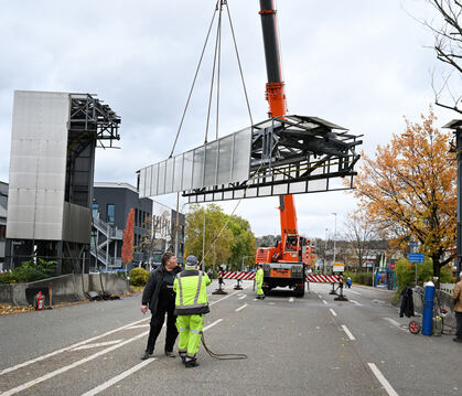 Nachdem kleine Schwierigkeiten überwunden wurde, schwebt die Brücke des Peoplemovers am Autokran langsam auf die Straße.
