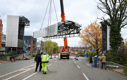 Nachdem kleine Schwierigkeiten überwunden wurde, schwebt die Brücke des Peoplemovers am Autokran langsam auf die Straße.