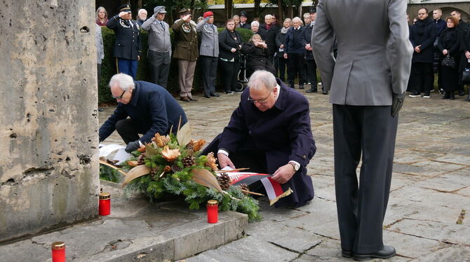 Jürgen Neumeister (links kniend) und OB Thomas Keck (rechts daneben) legten Kränze vor dem Mahnmal für die Opfer der Weltkriege
