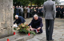 Jürgen Neumeister (links kniend) und OB Thomas Keck (rechts daneben) legten Kränze vor dem Mahnmal für die Opfer der Weltkriege