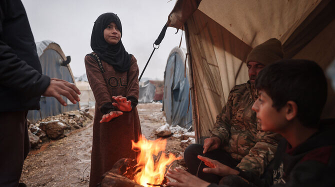 Syrische Binnenflüchtlinge wärmen sich an einem Feuer.  FOTO: ALKHARBOUTLI/DPA