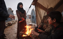 Syrische Binnenflüchtlinge wärmen sich an einem Feuer.  FOTO: ALKHARBOUTLI/DPA