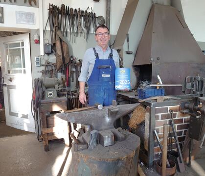 Josef Leippert mit der Plakette des Innenministers vor Amboss und Esse.