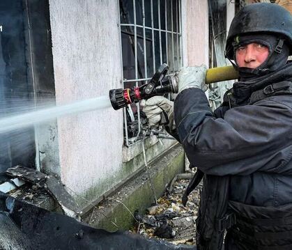 Feuerwehrmänner in Stahlhelmen und Splitterschutzwesten: Ein Bild von Löscharbeiten nach einem Angriff auf ein Werkstattgebäude