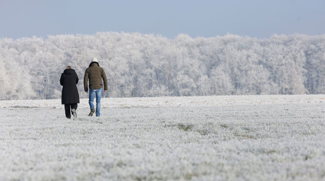 Spaziergänger sind bei Minusgraden im Schnee bei Pfronstetten unterwegs.