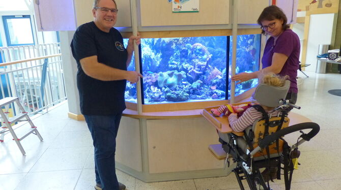 Fische, Aquarium, Kinderklinik, Tübingen Thomas Musch und Jutta Gaiser stehen mit einer kleinen Patientin beim Meerwasseraquarium im Foyer der Kinderklinik. FOTO: WEBER
