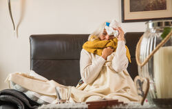 Eine Frau mit einer Erkältung auf einem Sofa